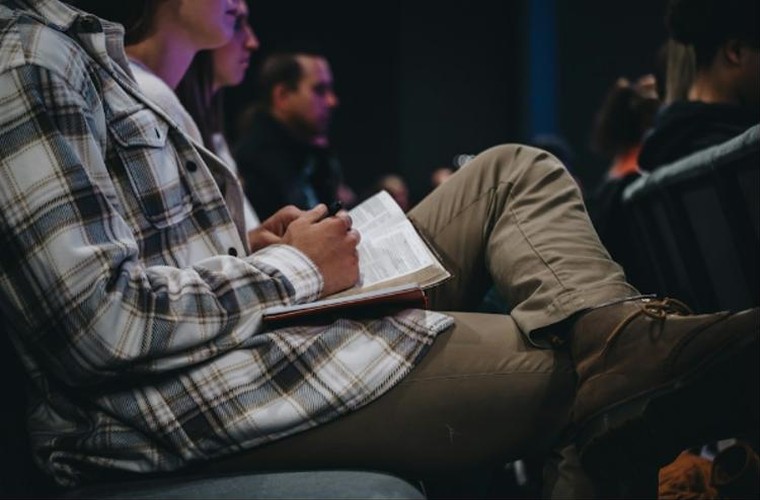 Joven leyendo la Biblia en la reunión